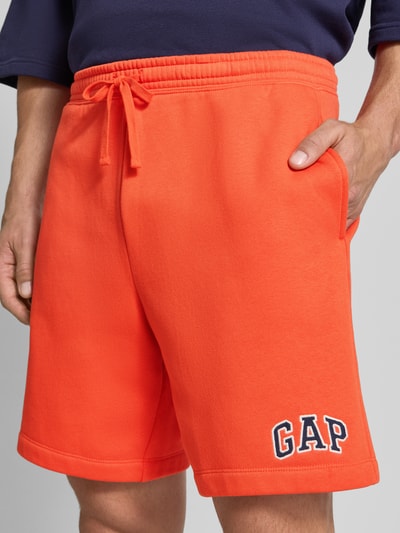 Mannenmodel draagt Straight fit korte broek met gestikt logo Model 'Heritage' van GAP, katoenmix, elastische band met tunnelkoord, detailopname bovenbeen.