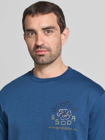 Männermodel trägt T-Shirt mit Label-Print und Rundhalsausschnitt van Scotch & Soda in blauw, puur katoen, regular fit, nahaufnahme bovenlichaam