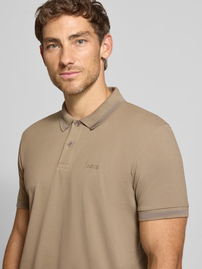 Männermodel trägt regular fit poloshirt uit pure katoen model 'PIO 1' van BOSS Green in beige met kraag, nahaufnahme bovenlichaam.