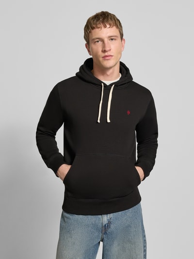 Männermodel trägt Hoodie mit Känguru-Tasche von REVIEW in Schwarz aus Baumwollmischung, Slim Fit, Kapuze, Tunnelzug, elastische Abschlüsse, Ganzkörperansicht von vorne.