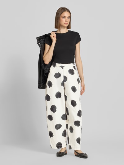Frauenmodel trägt Barrel Fit Jeans im Allover-Look Modell 'YARA' von Topshop, High Waist, weiß mit schwarzen Punkten, Ganzkörperansicht von vorne.