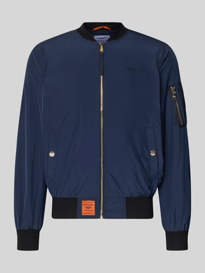 Produktfoto, Bomberjacke mit Label-Patch und Eingrifftaschen von Original Bombers, granatowy kolor, prosty krój, tkanina z fakturą, suwak, kieszenie z zatrzaskiem, kieszeń na rękawie, ściągacze, długość tyłu w rozmiarze M: 67 cm, szerokość ramion w rozmiarze M: 43 cm, szerokość w rozmiarze M: 53 cm, długość rękawa w rozmiarze M: 68 cm