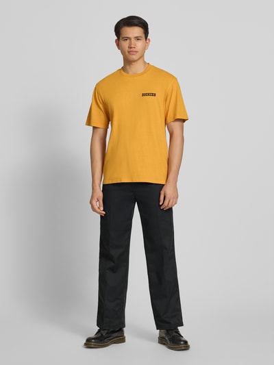 Männermodel trägt Loose Straight Fit Hose mit Bügelfalten von Dickies aus Material-Mix mit Baumwoll-Anteil, Eingrifftaschen, Ganzkörperansicht von vorne.