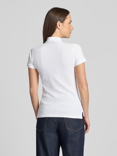 Vrouwenmodel draagt Slim Fit Poloshirt met Logo-Stitching model 'JULIE' van Polo Ralph Lauren van katoen-elastaanmix, uni wit, polokraag, korte knoopsluiting, geribde mouwuiteinden, ruglengte bij maat S 65 cm. Volledige lichaamsaanzicht achteraan.