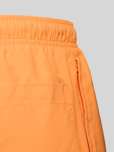 Produktfoto, Badehose mit Gesäßtasche und Logo-Stitching von MCNEAL in Orange, Loose-Fit, elastischer Bund mit Kordelzug, Detailaufnahme.