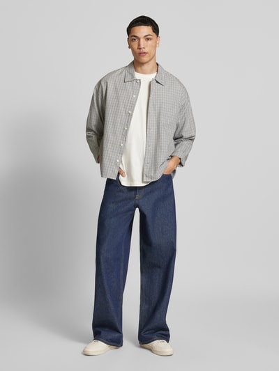 Männermodel trägt Regular Fit Freizeithemd aus Baumwolle Modell 'AUSTIN' von Jack & Jones, hellgrau kariert, Ganzkörperansicht von vorne.
