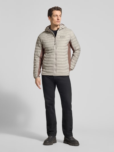 Mannermodel draagt Steppjacke mit Kapuze und Logo van Columbia in regular fit met capuchon, ritssluiting, logoprint; grijs-bruin, ruglengte maat M 72 cm, schouderbreedte 47 cm, borstwijdte 52 cm, mouwlengte 69 cm; ganzkörperaanzicht van voren.