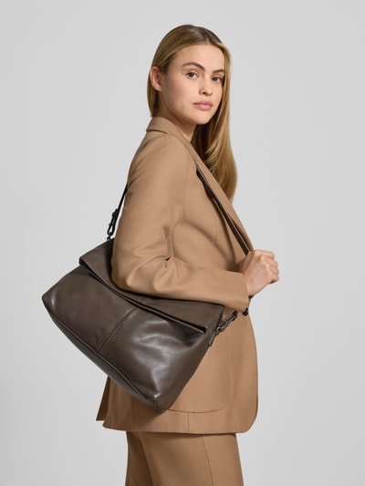 Frauenmodel trägt Crossbody Bag aus echtem Leder Modell 'Fiona' von LIEBESKIND BERLIN in Braun, mit Magnetverschluss und Logo-Prägung, Ganzkörperansicht Rückansicht.