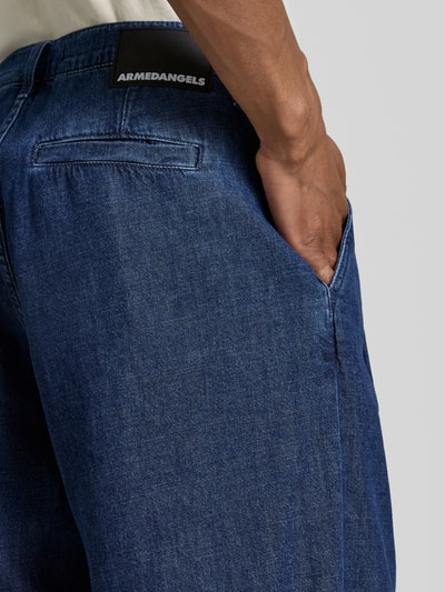 Männermodel trägt Regular Fit Jeans-Bermudas aus Baumwoll-Lyocell-Mix Modell 'DENIM' von Armedangels, stylizowana na denim, mieszanka bawełny i lyocellu, naszywka z logo, 5 kieszeni, szlufki na pasek, zapięcie na guzik i zamek błyskawiczny, detal tylnej kieszeni, zbliżenie pleców, detailaufnahme.