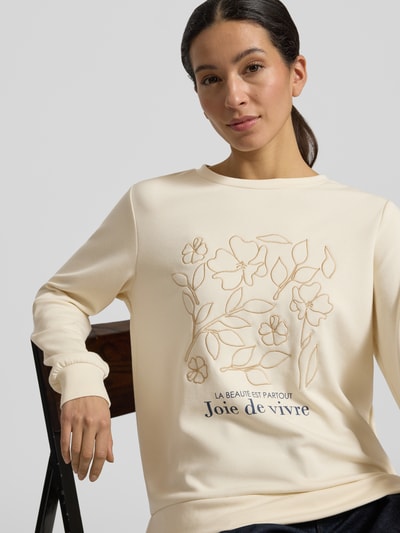 Frauenmodel trägt Sweatshirt mit Label-Print Modell 'BANU' von Soyaconcept in Creme mit floralen Konturen, lockerer Schnitt, Nahaufnahme Oberkörper.