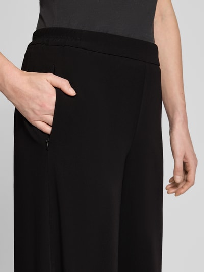 Frauenmodel trägt Stoffhose in verkürzter Passform Modell 'Coralie' von MAC, schwarzer Material-Mix mit Stretch, Nahaufnahme Hüfte, lockerer Schnitt, elastischer Bund, Nahtreißverschlusstasche, Kontext Damen Stoffhose mit kurzer Innenbeinlänge bei Größe 36.