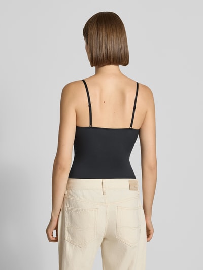 Frauenmodel trägt Body mit Spitze Modell 'LILI' von PIECES in Schwarz zu heller Hose, glatte Stoffstruktur, Ganzkörperansicht Rückansicht.