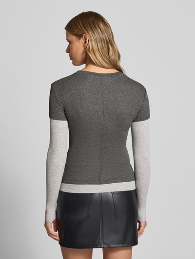 Modelka kobieca ma na sobie Langarmshirt aus Viskose-Mix mit Ripp-Struktur Modell 'Belia' od Topshop w kolorach szarym i ciemnoszarym, z okrągłym dekoltem, 2-w-1-look, cienka prążkowana faktura, długość tyłu w rozmiarze S: 55 cm, krój slim fit; widok całej sylwetki od tyłu.