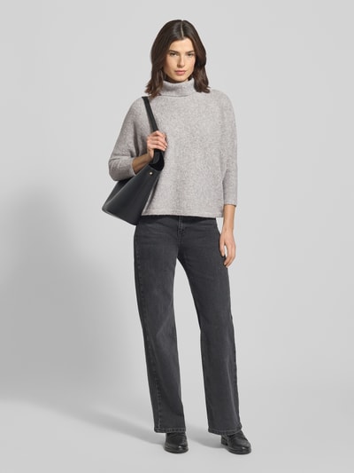 Modelka nosi Oversized Rollkragenpullover mit Woll-Anteil Modell 'Tiola' od Someday, elastyczna mieszanka materiałów z wełną, luźny krój, szary kolor, dzianinowa struktura, całkowity widok z przodu.