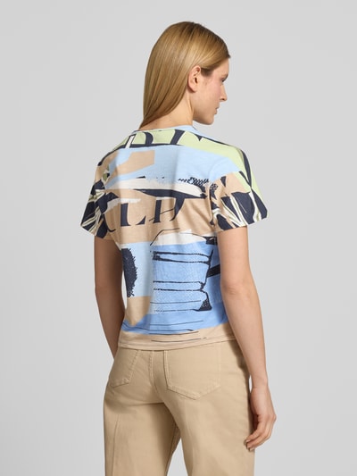 Modelka nosi T-Shirt im Allover-Look mit Rundhalsausschnitt von Betty Barclay, damski t-shirt z mieszanki bawełny i mikromodalu, krój regular fit, wzór na całej powierzchni, okrągły dekolt, długość tyłu w rozmiarze 36: 56 cm, jasnoniebieskie, beżowe i granatowe barwy, tekstura miękka, całkowity widok z tyłu.