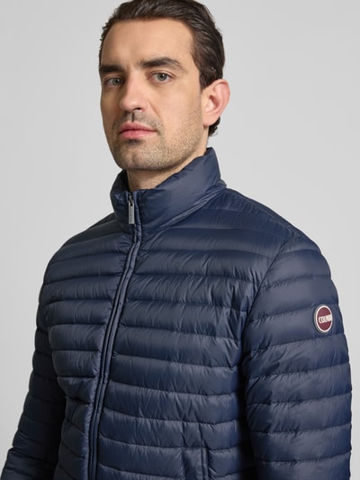 Männermodel trägt Steppjacke mit Zweiwege-Reißverschluss von Colmar Originals in Dunkelblau, Stehkragen, Eingrifftaschen, Nahaufnahme Oberkörper. Rückenlänge 65 cm, Schulterbreite 47 cm, Brustweite 43 cm, Ärmellänge 67 cm bei Größe 50. Regular Fit.