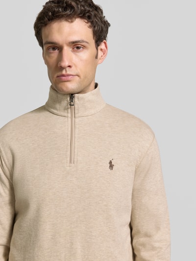 Männermodel trägt Regular Fit Sweatshirt aus Baumwoll-Mix von Polo Ralph Lauren in Beige mit sichtbarem Markenlogo, Nahaufnahme Oberkörper. Herren Sweatshirt von Polo Ralph Lauren.