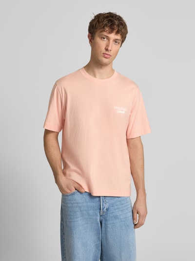 Männermodel trägt T-Shirt mit Statement-Print Modell 'NORREBRO' von Jack & Jones aus Reine Baumwolle im Gerader-Schnitt, Rundhalsausschnitt, Pastellrosa, glatte Textur, Rückenlänge Größe M 68 cm, Ganzkörperansicht von vorne.