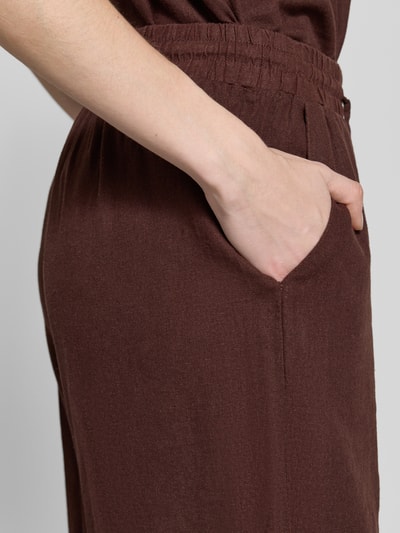 Frauenmodel trägt Leinenshorts mit elastischem Bund Modell 'Lava' von FREE/QUENT in Braun, Leinen-Mix mit Viskose-Anteil, Loose-Fit, französische Eingrifftaschen, Nahaufnahme Hüftbereich, Kontext: Damen Leinenshorts, elastischer Bund mit Kordelzug, Bundweite Größe S 39 cm, Innenbeinlänge 50 cm.