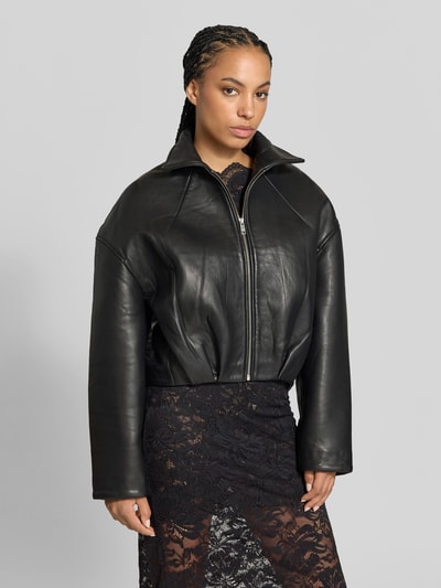 Frauenmodel trägt Cropped Lederjacke aus echtem Leder von ROTATE, schwarze Ziegenveloursjacke mit hohem Stehkragen, Boxy Fit, ganzkörperansicht von vorne.