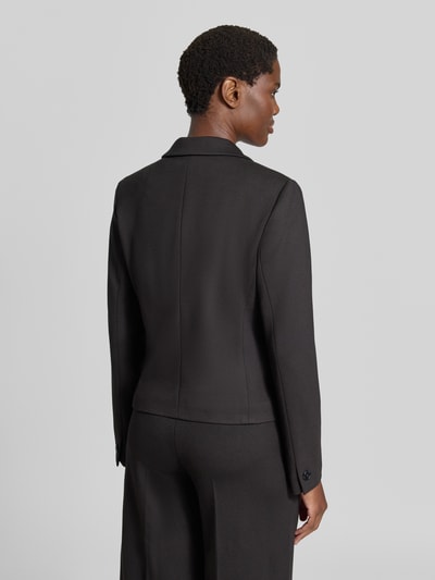 Frauenmodel trägt Blazer aus Viskose-Mix mit Reverskragen von MORE & MORE, tailliert, schwarze Farbe, Ganzkörperansicht Rückansicht.