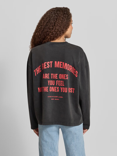 Frauenmodel trägt Oversized Longsleeve mit Logo-Print Modell 'Memories' von Karo Kauer aus reiner Baumwolle, oversize, schwarz mit rotem Print, Rückenlänge bei Größe S 63 cm, Ganzkörperansicht Rückansicht.