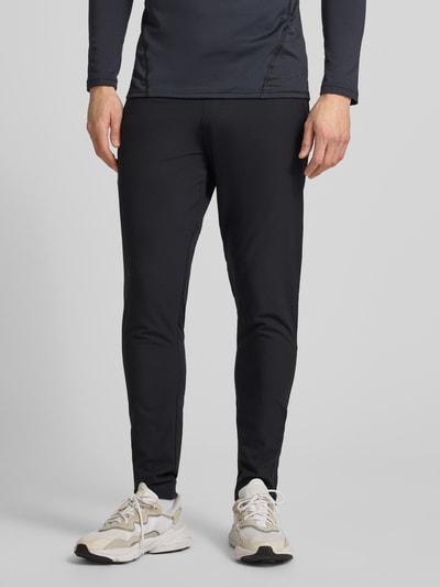 Männermodel draagt Trainingshose mit Reißverschlusstaschen van Under Armour, regular fit met elastische band, zwarte kleur, Ganzkörperansicht van voren.