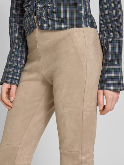 Kobieta nosi Slim Fit Hose in verkürzter Passform od Christian Berg Woman, elastyczna mieszanka materiałów, imitacja weluru, krój slim fit, skrócony krój, szerokość w rozmiarze 36: 37 cm, długość wewnętrzna nogawki w rozmiarze 36: 73 cm, beżowe spodnie o gładkiej teksturze, detailaufnahme okolic bioder