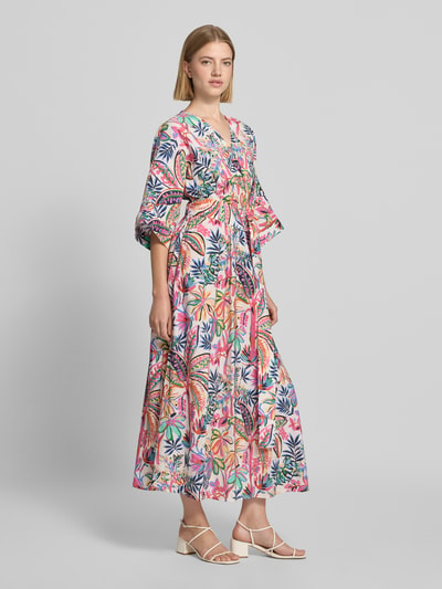 Frauenmodel trägt Midikleid aus Viskose-Mix mit floralem Allover-Print von Milano Italy, bunte Farben, tailliert, Halbarm, Ganzkörperansicht von vorne.