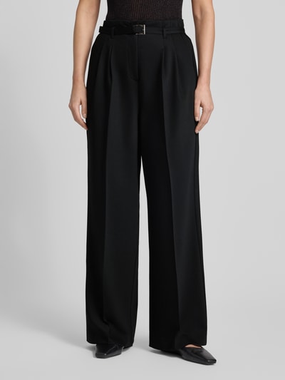 Frauenmodel trägt schwarze Stoffhose mit Gesäßtaschen von More & More, lockerer Schnitt, Stoffgürtel, Nahaufnahme Oberkörper, Material-Mix mit Viskose-Anteil, französische Eingrifftaschen.