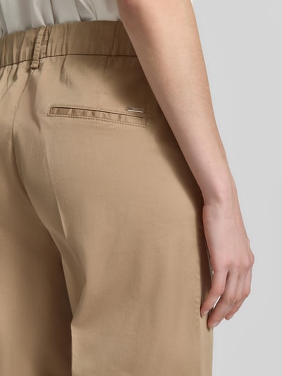 Frauenmodel trägt Chino mit Bügelfalten von Brax, beige, Baumwoll-Mix mit Lyocell-Anteil, Ziertaschen, Nahaufnahme Rückansicht.
