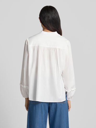 Frauenmodel trägt Regular Fit Bluse aus Baumwoll-Mix mit Rüschenbesatz von MORE & MORE in Weiß, lockerer Schnitt, Stehkragen, lange Ärmel, Ganzkörperansicht Rückansicht. Elastischer Baumwoll-Mix, Rückenlänge 65 cm, Ärmellänge 60 cm, durchgängige Knopfleiste.