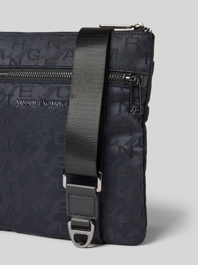 Produktfoto, Handtasche mit Logo-Muster und Label-Applikation von Armani Exchange, dunkle Farben, strukturierte Oberfläche, Hauptfach mit Reißverschluss, Außenfach, Schulterriemen, Maße: 21 cm Breite, 23 cm Länge, 2 cm Tiefe, Riemenlänge 102 cm