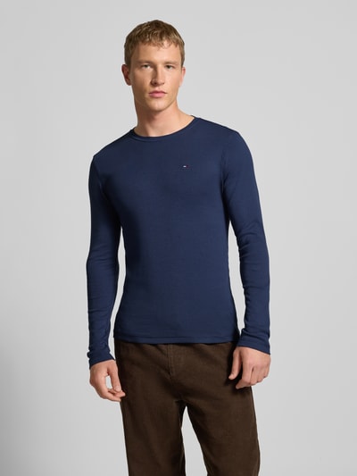 Męski model nosi Slim Fit Longsleeve mit Rippenstruktur od Tommy Jeans z bawełny, okrągły dekolt, wyhaftowane logo, całość z przodu, Ganzkörperansicht von vorne.