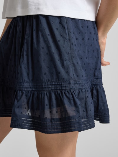 Frauenmodel trägt Regular Fit Mini-Skort aus reiner Baumwolle Modell 'KATTI' von Only in Dunkelblau, Strukturmuster gestickt, Nahaufnahme Oberschenkel.