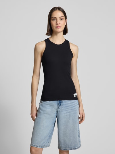 Frauenmodel trägt Slim Fit Tank Top aus Baumwoll-Mix Modell 'KANITAA' von Armedangels, Optik: Unifarben, Feinripp, U-Ausschnitt, Label-Patch, Logo-Stitching, schmale Träger, Ganzkörperansicht von vorne.