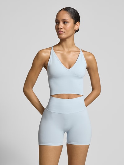 Frauenmodel trägt Crop Top mit überkreuzten Trägern von aim'n in hellblauem Material-Mix mit Stretch, V-Ausschnitt, Nahaufnahme Oberkörper.