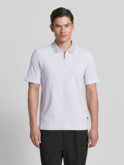 Mężczyzna nosi Regular Fit Poloshirt mit Reißverschluss von MAERZ Muenchen, dwa kolory, fakturowany wzór, zamek błyskawiczny, długość tyłu 74 cm w rozmiarze 50, widok całej sylwetki z przodu.