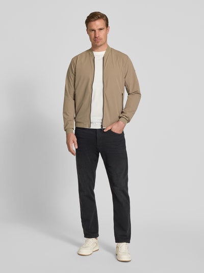 Männermodel trägt Regular Fit Jacke mit Stehkragen Modell 'Campo' von SCANDINAVIAN EDITION in Beige, Zweiwege-Reißverschluss, Eingrifftaschen, elastische Abschlüsse, Rückenlänge 67 cm, Schulterbreite 44 cm, Brustweite 51 cm, Ärmellänge 64 cm, Ganzkörperansicht von vorne.