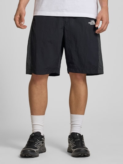 Männermodel trägt schwarze Shorts mit Logo und Gürtel von The North Face, Regular Fit, elastischer Bund, Ganzkörperansicht von vorne.