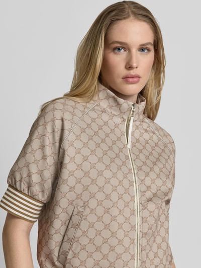 Frauenmodel trägt Jacke mit 1/2-Arm Modell 'Tayla' von JOOP!, Logo-Muster, beiger Material-Mix, Stehkragen, Nahaufnahme Oberkörper.
