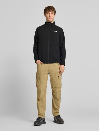Männermodel trägt Jacke mit Raglanärmeln und Logo-Print Modell 'PACKABLE KECHA' von The North Face, Schwarz, Material-Mix mit Stretch-Anteil, Gerader-Schnitt, Stehkragen, Reißverschluss, Rückenlänge bei Größe M 68 cm, Ärmellänge bei Größe M 72 cm, Ganzkörperansicht von vorne.