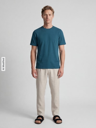 Männermodel trägt T-Shirt mit Rundhalsausschnitt von MCNEAL aus reiner Baumwolle in Blau, Slim Fit, helle Hose, Ganzkörperansicht von vorne.