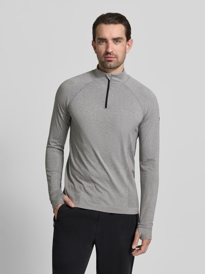 Männermodel trägt Langarmshirt mit Troyer Modell 'THE TRAINING DAY QUARTER' von Fabletics, Material-Mix, Regular-Fit, Grau, Ganzkörperansicht von vorne. Rückenlänge bei Größe M: 71 cm, Raglanärmel, Label-Detail.