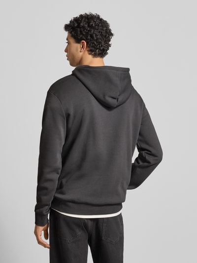 Männermodel trägt Regular Fit Hoodie aus Baumwoll-Mix Modell 'CERES' von Only & Sons, uni, label stitching, kangoeroezak, capuchon, sweat, zwart, ganzkörperansicht rückansicht.