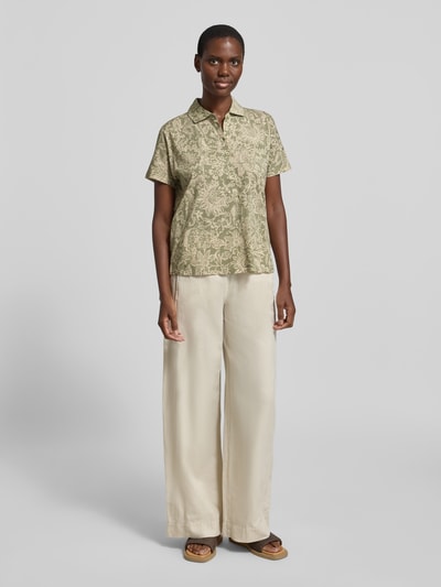 Frauenmodel trägt Relaxed Fit Poloshirt aus reiner Baumwolle von Marc O'Polo, Optik:Allover-Muster, florales Muster, Kurzarm, Polokragen, V-Ausschnitt, Jersey, Ganzkörperansicht von vorne.