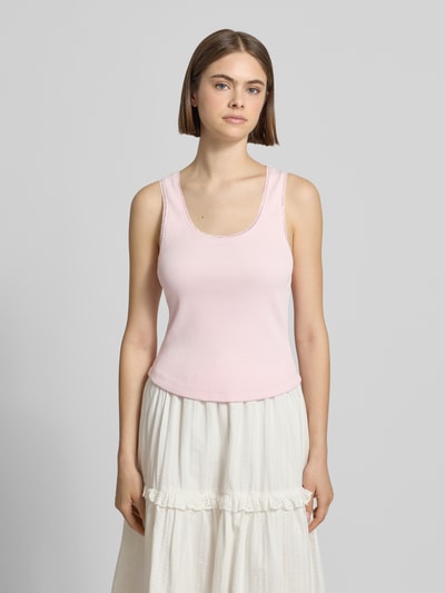 Frauenmodel trägt Tanktop in Ripp-Optik Modell 'Jolie' von OH APRIL aus Baumwoll-Elasthan-Mix, Slim-Fit, Spitzenbesatz, Rundhalsausschnitt, Rückenlänge bei Größe S 52 cm, zartrosa, glatte Struktur, unten ausgestellter weißer Rock, Ganzkörperansicht von vorne.