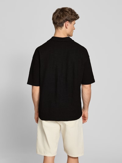 Männermodel trägt Regular Fit Freizeithemd mit Label-Patch Modell 'LIBCO' von Pegador, Schwarz, Material-Mix, Rückenansicht, Ganzkörperansicht Rückansicht. Rückenlänge bei Größe M: 72 cm, Schulterbreite: 41 cm, Ärmellänge: 35 cm, Kurzärmelig, Reverskragen, Knopfleiste.