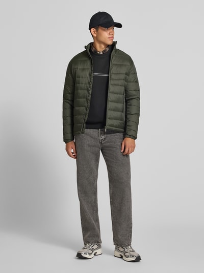 Männermodel trägt Relaxed Fit Sweatshirt mit Viskose-Anteil Modell 'Fusion' von JACK & JONES, Mieszanka materiałów z dodatkiem wiskozy, krój relaxed fit, nadruk z logo, krój z długim rękawem, elastyczne wykończenia, długość tyłu w rozmiarze M: 66 cm, długość rękawów w rozmiarze M: 66 cm, widoczne zielenie, czernie i szarości, proste cięcia, tekstura matowa, cała sylwetka z przodu.