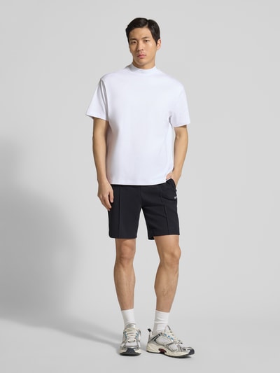 Männermodel trägt schwarze Regular Fit Shorts aus Baumwoll-Mix Modell 'T_JOIN Headlo' von BOSS Green mit Kontraststreifen und Tunnelzug, Ganzkörperansicht von vorne.